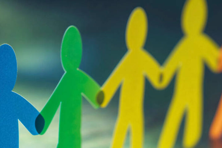 Colorful paper figures holding hands in a line, symbolizing diversity and unity.
