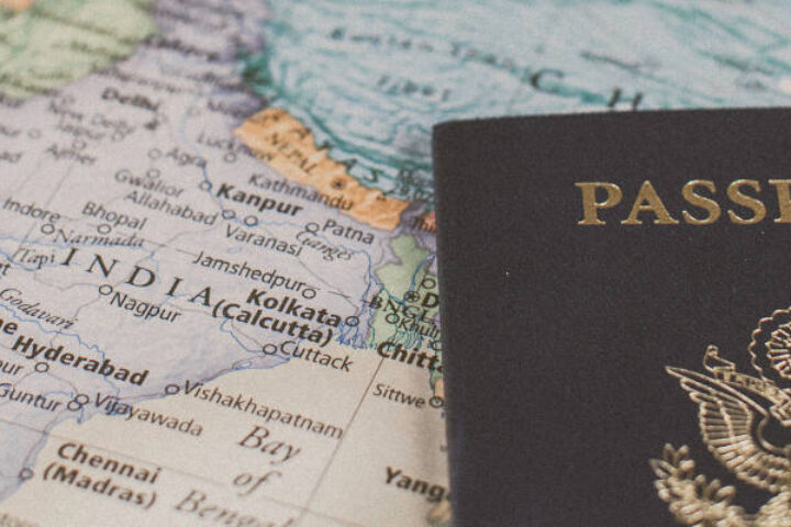 Passport resting on an open world map, crest visible on cover, suggesting travel documentation.